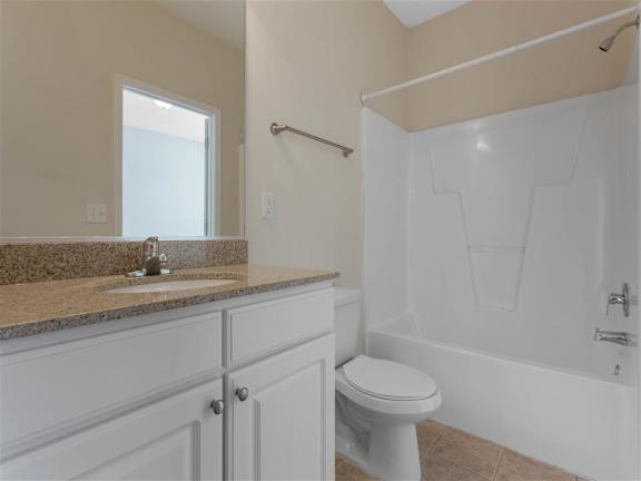 Bathroom with Bathtub and Shower Tan Counters White Cabinets and Linen Closet Door