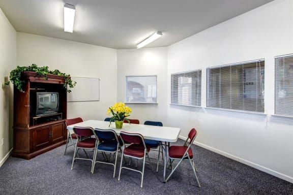 Resident Lounge Room with Large Windows Folding Table and Chairs in Front of a TV in an Entertainment Center