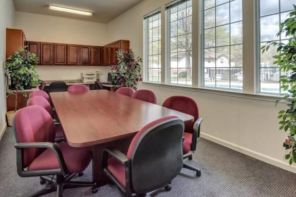 Conference Room with Large Table and Rolling Chairs Decorative Trees and Large Windows