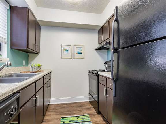 Fully Equipped Kitchen with Brown Cabinets and Black Appliances at Regency Park Apartment Homes, Raleigh, NC, 27616