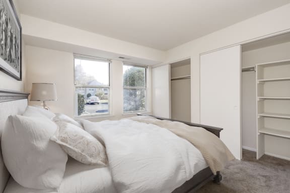 staged bedroom with carpeted flooring, window, and closet with built-in shelves