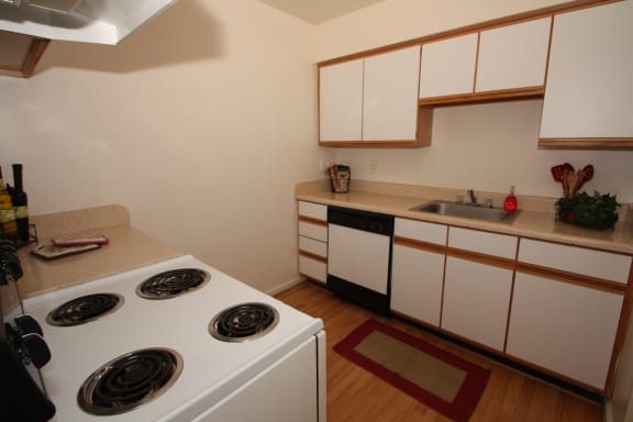 kitchen with white cabinets, wood-style flooring and white stove top.