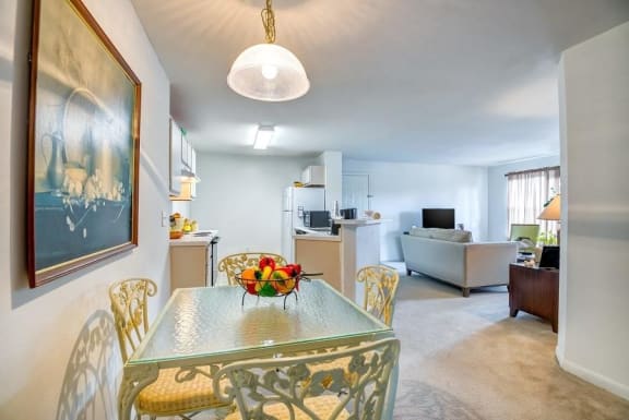 Model Dining Room with Table and Chairs with Kitchen and Furnished Living Room in the Background