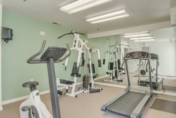 The fitness center is carpeted throughout with one picture window on the same wall as the entry door. The fitness center is equipped with a treadmill, a stationary bicycle, an elliptical and a weightlifting machine.