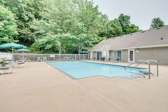 A swimming pool surrounded by a green fence and trees.