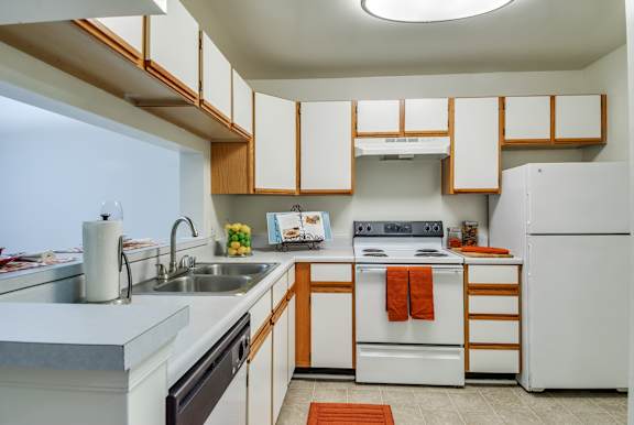 A kitchen with white appliances and wooden cabinets.