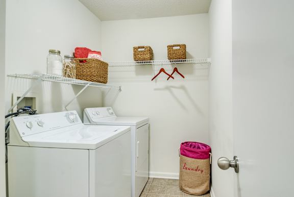 Laundry room with washer and dryer and basket baskets on shelves.
