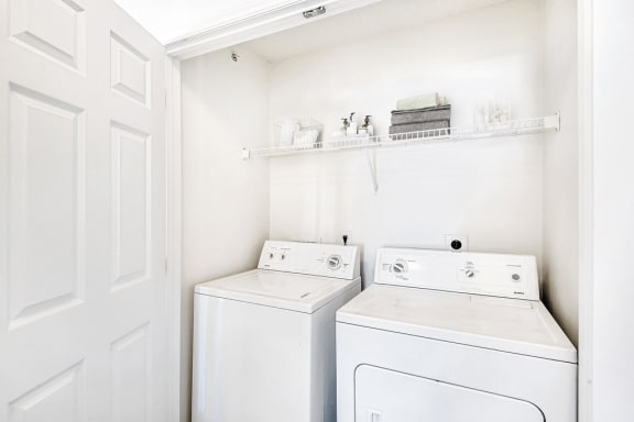 Virtually staged Utility Closet with White Wire Shelf Over Full Sized Washer and Dryer