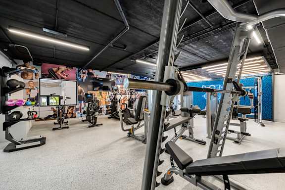 a gym with weights and other exercise equipments in a building with a gym wall
