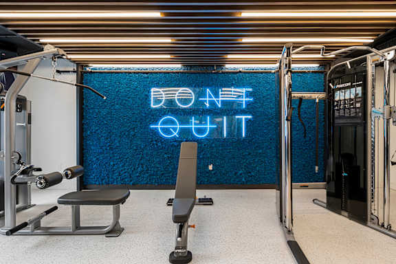 a gym with a blue neon sign on the wall and a gym chair