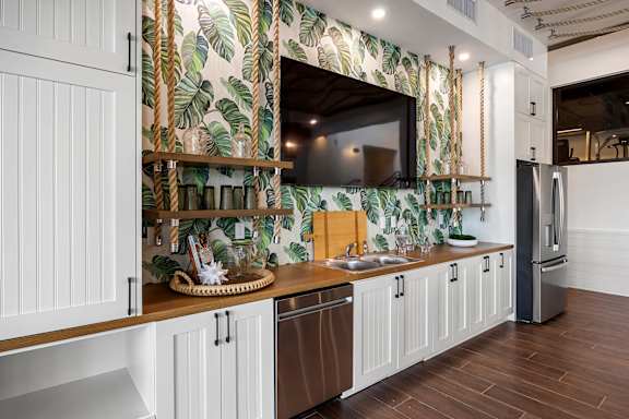 a kitchen with white cabinets and a sink and a television