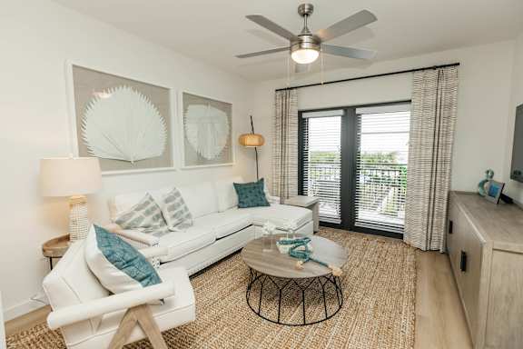 a living room with a white couch and a ceiling fan