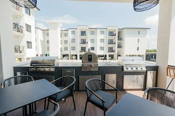 a patio with a grill and tables with chairs