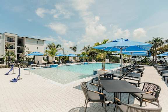 a swimming pool with tables and umbrellas