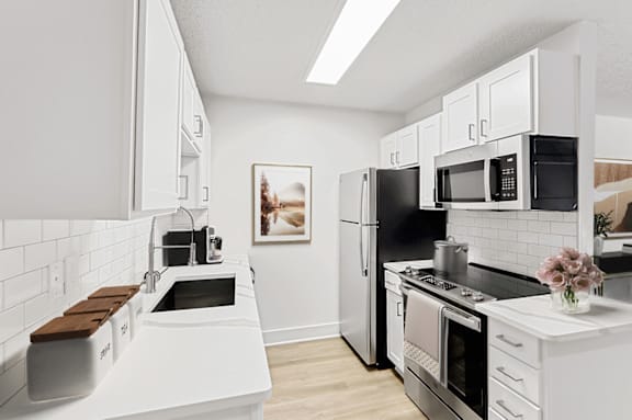 a kitchen with white cabinets and stainless steel appliances at The Parke at Trinity Apartment Homes, North Carolina