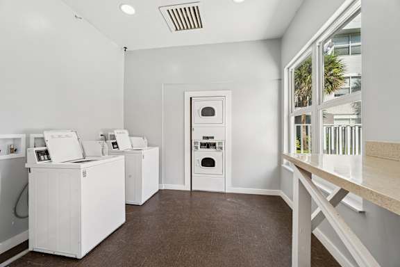 A room with a white wall and brown floor with a white oven and fridge.