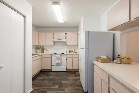A kitchen with a white refrigerator and wooden floors.