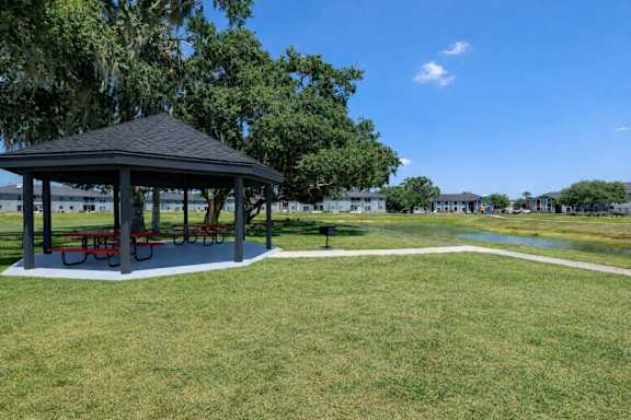 A gazebo with red benches is surrounded by a grassy area.