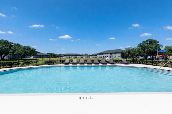 A swimming pool with a blue sky and clouds in the background.