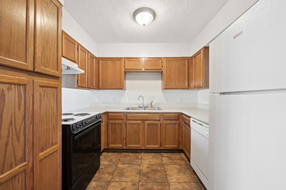 an empty kitchen with wooden cabinets and white appliances at Patriot Point Apartment Homes, North Carolina