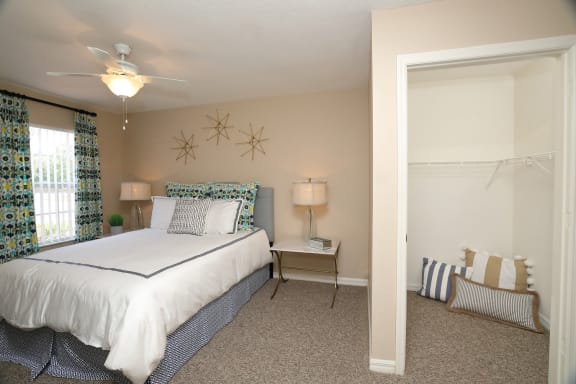 The Bedroom is a comfortable space with a large bed centered on the main wall. A large window brings plenty of natural light into the room. The carpeted flooring continues into the walk-in closet.