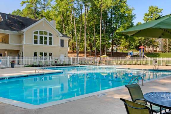 Leasing Office Exterior with Swimming Pool and Sun Deck with Lounge Chairs with Trees and Building Exteriors in the Background at Regency Park Apartment Homes, Raleigh, NC