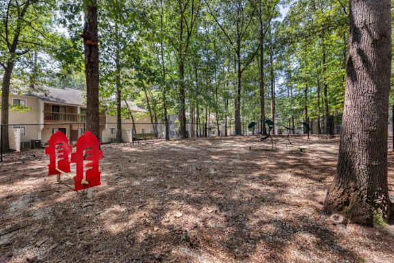 Fenced in Dog Park with Mulch and Agility Equipment Shaded by Tall Trees at Regency Park Apartment Homes, Raleigh, 27616