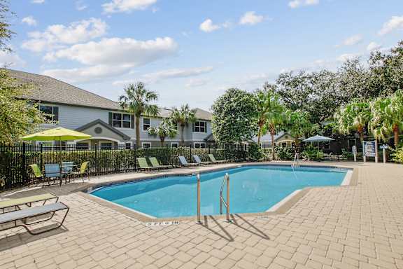 A swimming pool surrounded by a brick patio and lounge chairs.