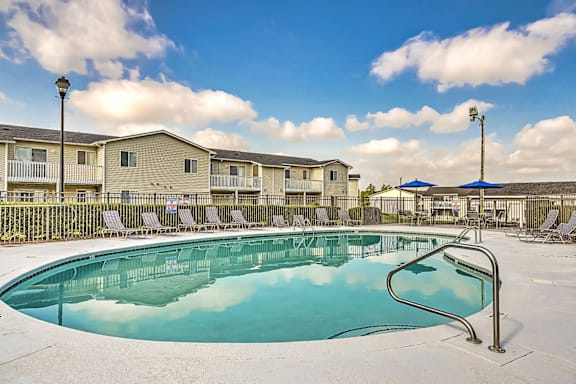 A swimming pool surrounded by chairs and apartment buildings.at Patriot Point Apartment Homes, North Carolina