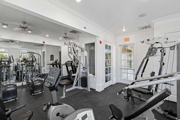 A gym with a variety of equipment including treadmills, weights, and exercise machines.