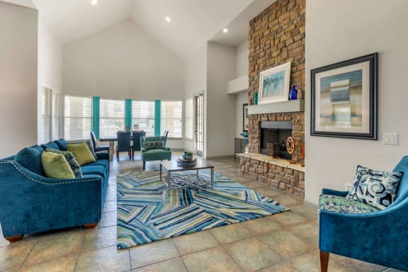 Clubhouse Seating Area with Large Windows and Natural Light Blue Couches and Armchairs  Around Fireplace