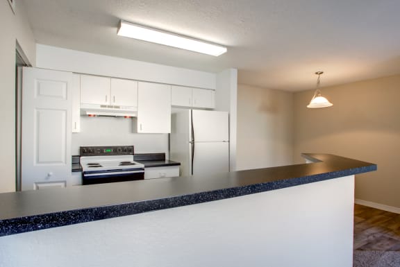 a kitchen with white cabinets and a black counter top