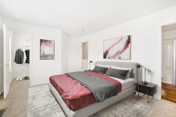a bedroom with white walls and a gray bed with a red blanket