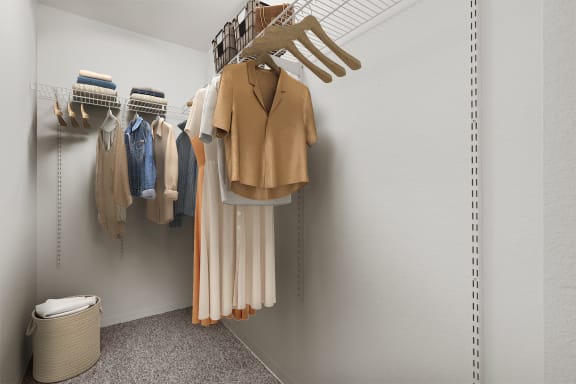 a walk in closet with a coat rack and clothes hanging on the wall