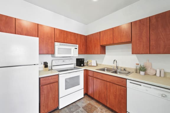 kitchen with white appliances, wood cabinetry, and tile flooring