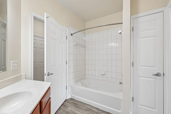 A white bathroom with a tub, sink, and shower.