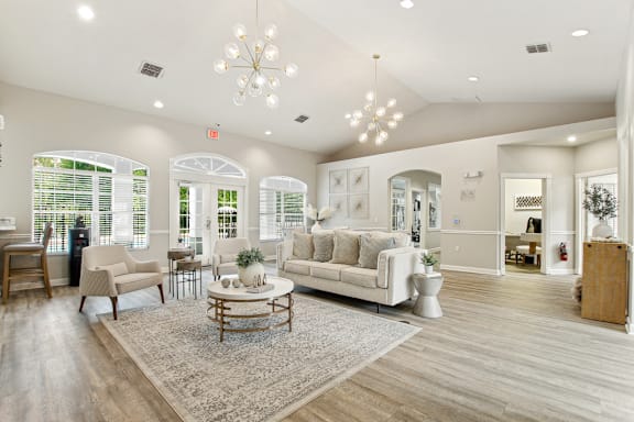 A spacious living room with a white sofa, wooden coffee table, and a chandelier.