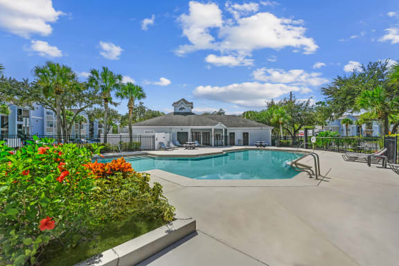 Pool area with tanning chairs on the deck surrounded by natural landscaping
