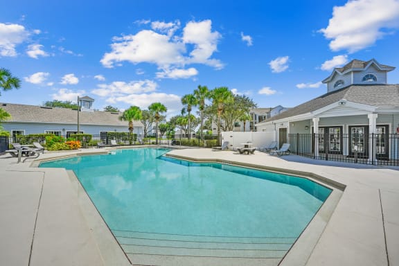 Pool area with tanning chairs on the deck surrounded by natural landscaping