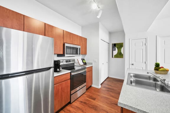 kitchen with hardwood-style flooring, wood cabinetry, and stainless steel appliances