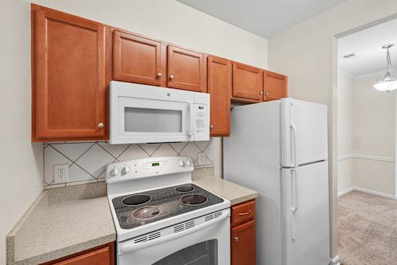 A kitchen with a white refrigerator, white microwave, and white stove.