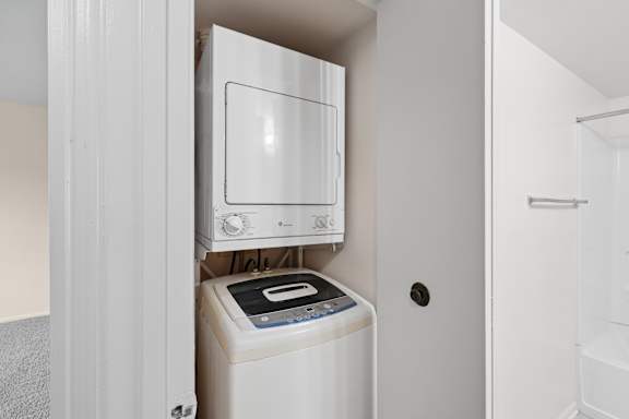 A white microwave oven is built into a cabinet above a washing machine.