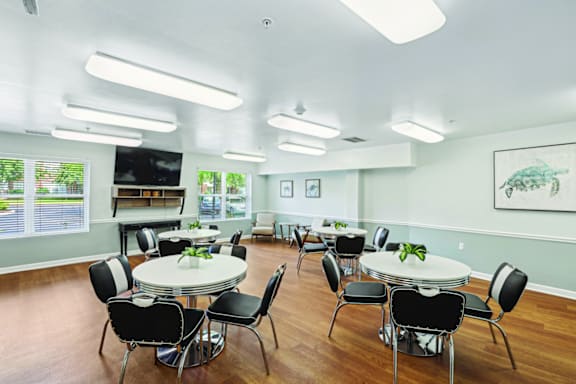 A room with tables and chairs and a painting on the wall.