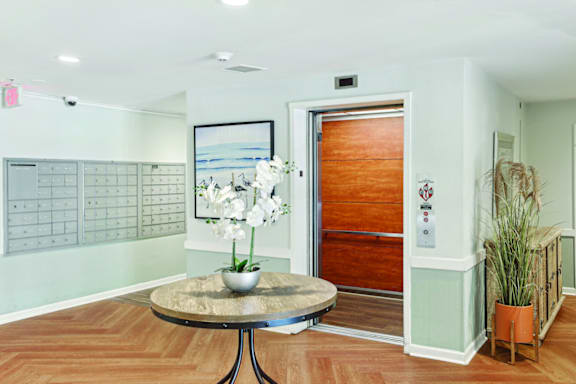 A room with a wooden floor and a round table with a vase of flowers on it.