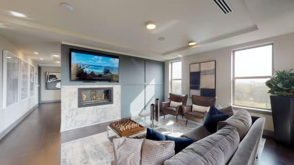 Resident sky lounge facing a table and sitting area complete with a television and fireplace.