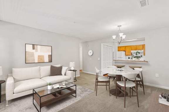 a living room with a white couch and a dining room table with chairs
