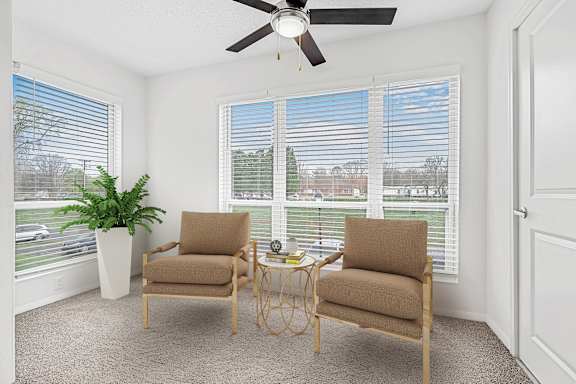 A room with two chairs and a table in front of a window with blinds.