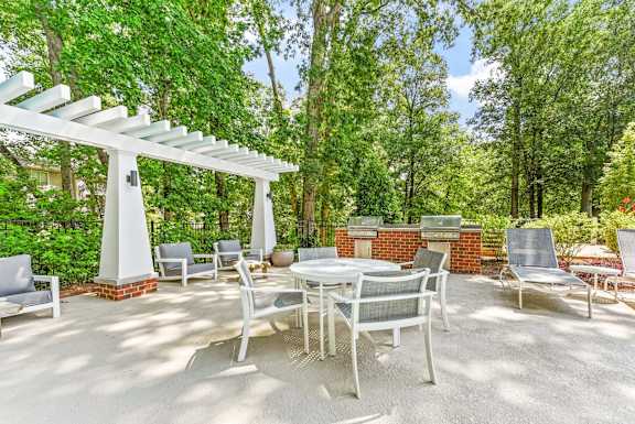 A patio with a table and chairs under a white pergola.