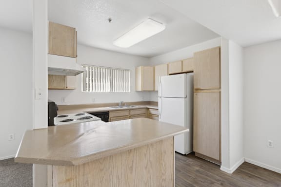 white refrigerator and wooden cabinets in kitchen at The Village at Sun Valley Apartments, Mesa Arizona