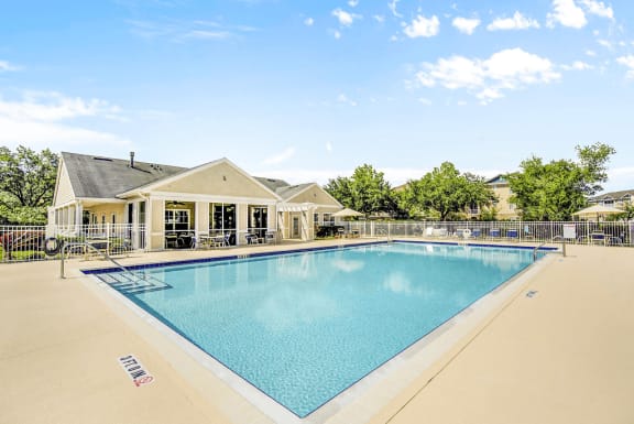 Swimming pool with lounge seating surrounded by native landscape and clubhouse in background